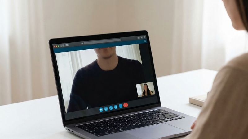 Osoba korzystająca z laptopa przy biurku, rozmowa wideo z terapeutą, spokojne domowe wnętrze