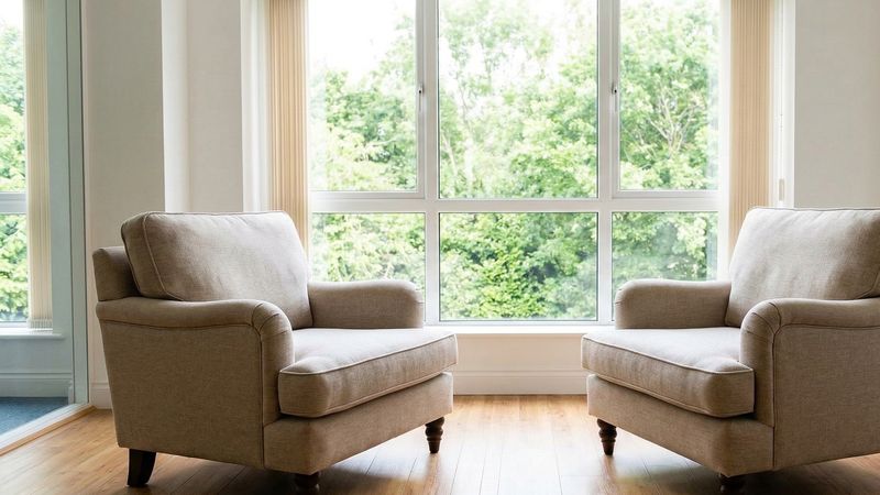 Dwa wygodne fotele naprzeciwko siebie w jasnym gabinecie, duże okno z widokiem na zieleń